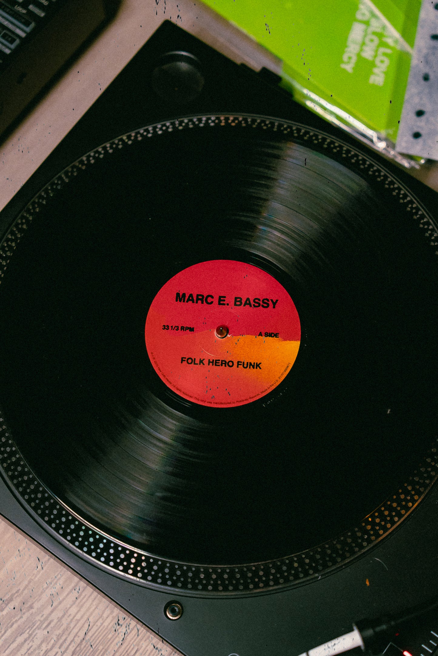 Marc E Bassy's album Folk Hero Funk vinyl record on a turntable