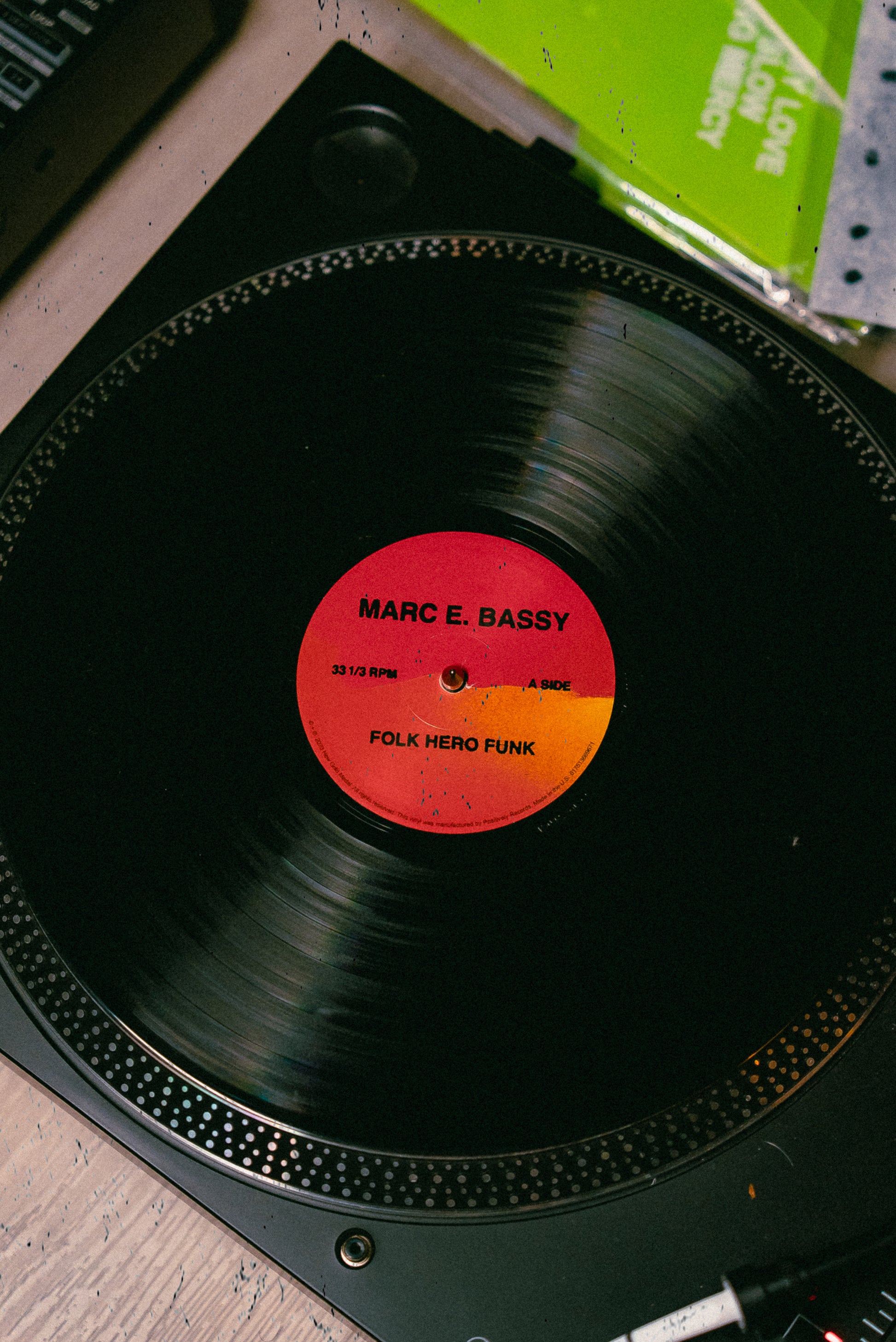 Marc E Bassy's album Folk Hero Funk vinyl record on a turntable